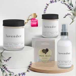 May include: A collection of lavender-scented products, including candles, a room spray, a wax melt, and a car air freshener. The candles and spray are in clear glass bottles with black lids and labels. The wax melt is heart-shaped.