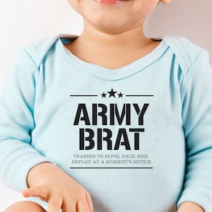 Può includere: Un body per neonato di colore azzurro chiaro con testo nero che recita "Army Brat" e "Trained to move, pack and deploy at a moment's notice".