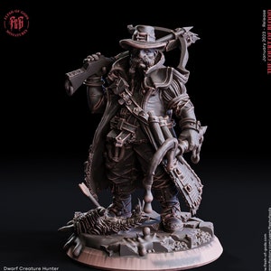 Op de afbeelding: Een gedetailleerd miniatuurbeeldje van een dwerg-kreaturenjager, geschilderd in bruine en zwarte tinten. De dwerg houdt een geweer en een grote bijl vast en staat op een rotsachtige basis. Het miniatuur is 25 mm hoog.