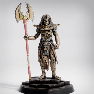 May include: A detailed figurine of a skeletal pharaoh holding a large battle axe. The figure is clad in ornate armor and wrapped in bandages, standing on a black base. The axe has a gold blade and a pink and gold handle.