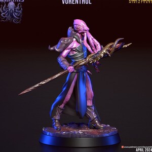 Peut inclure: Figurine miniature de Vorenthul, un extraterrestre humanoïde à la peau rose et aux tentacules, tenant un bâton. La figurine porte une armure et une robe fluide bleue et noire. La base est sombre avec une lueur bleue.