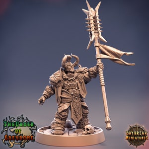 Puede incluir: Una figura miniatura de un guerrero con un casco con cuernos, que lleva armadura y sostiene una lanza con p&uacute;as y una bandera. La figura est&aacute; pintada de color marr&oacute;n y se encuentra sobre una base redonda.