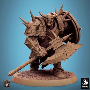 May include: A detailed miniature of an Orc warrior, painted in brown tones. The Orc is wearing heavy armor with spikes and holding a large axe. The miniature is standing on a round base.