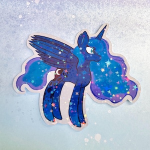 May include: A holographic sticker featuring a stylized illustration of a blue pony with a flowing mane and tail. The pony has wings, a horn, and a crescent moon symbol. The design is covered in sparkling stars.