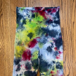 May include: A pair of tie-dye leggings in shades of blue, green, yellow, and red. The leggings have a high waist and a cropped length.