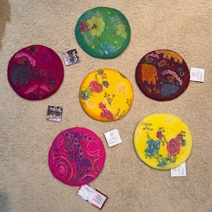 May include: Six round felt coasters with different colorful designs. The coasters are approximately 10 inches in diameter and feature floral, geometric, and animal patterns.
