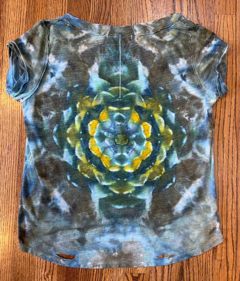 May include: A blue, green, and yellow tie-dye t-shirt with a circular pattern in the center. The shirt has a distressed look with frayed edges and holes.