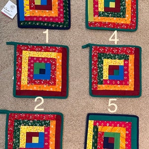 May include: Six colorful quilted pot holders with a log cabin pattern. Each pot holder has a different color scheme and is numbered 1 through 6.