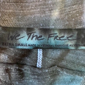 May include: A close-up of a dark green and white tie-dye shirt tag with the text "We The Free" and "Small Made in Vietnam - Fabrique au Vietnam".