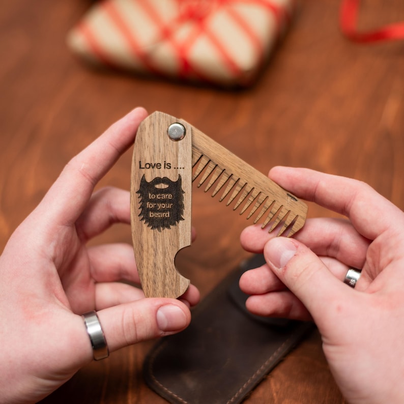 May include: A wooden beard comb with a bottle opener. The comb has a message that reads "Love is... to care for your beard".
