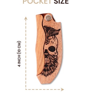 Może przedstawiać: Drewniany scyzoryk z motywem czaszki. N&oacute;ż ma 10 cm długości i 3,9 cm szerokości. Tekst "POCKET SIZE" jest wyświetlany nad nożem.