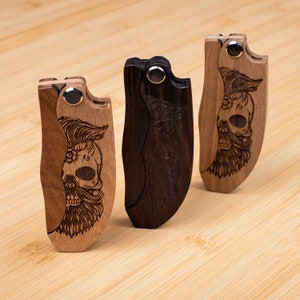 May include: Three wooden pocket combs with a skull and beard design. The combs are made of dark wood and light wood.
