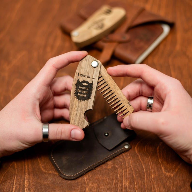May include: A wooden beard comb and bottle opener with a  "Love is... to care for your beard" inscription. The comb is folded and held in a person's hand.
