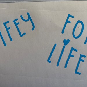 May include: A white card with the words "WIFEY FOR LIFEY" written in blue with a small blue heart above each word.