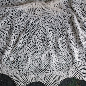 Puede incluir: Mantel de encaje blanco con un delicado patrón de hojas. El mantel está hecho de hilo fino y tiene un borde festoneado.