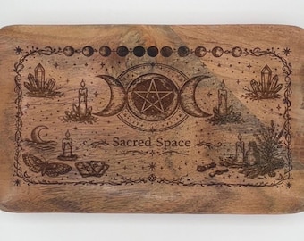 May include: Wooden rectangular tray with engraved celestial and mystical symbols. Features a triple moon design, a pentagram, crystals, candles, and the text "Sacred Space". The tray is brown with a natural wood grain.