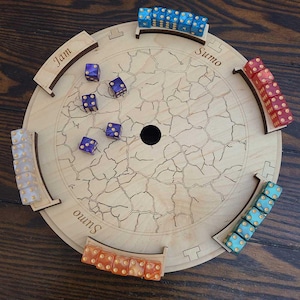 May include: A wooden game board with a cracked surface and four curved tracks around the perimeter. The tracks are labeled "Jam", "Sumo", "Sumo", and "Sumo". There are dice in various colors on the board and in the tracks.