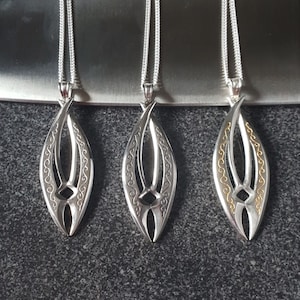 May include: Three silver pendants with a leaf-shaped design. The pendants have intricate details and are on silver chains. One pendant has gold accents.