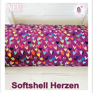 Könnte beinhalten: Ein Nahaufnahme eines violetten Stoffes mit einem Muster aus bunten Herzen. Der Stoff ist mit "Softshell Herzen" und "NEU" beschriftet.