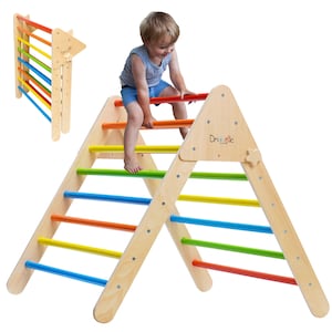 May include: A wooden triangular climbing frame with rainbow colored rungs. A young child is climbing the frame. The frame is labeled "Drielle".