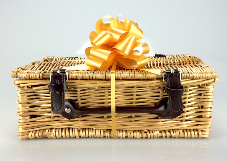 Puede incluir: Una cesta de mimbre con asa de cuero marr&oacute;n y lazo de cinta dorada. La cesta est&aacute; vac&iacute;a y lista para llenarse de regalos.