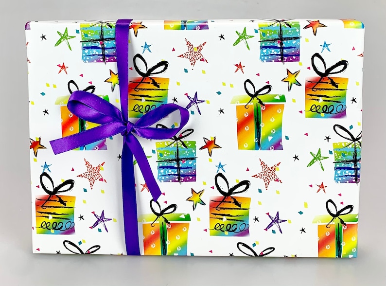 May include: A wrapped gift with a white background featuring a colorful pattern of gift boxes, stars, and confetti. The gift is tied with a vibrant purple satin ribbon and bow, creating a festive presentation.