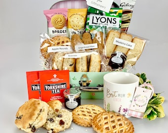 Può includere: Un cesto regalo pieno di varie prelibatezze, tra cui biscotti, focaccine, omini di pan di zenzero e tè. Il cesto contiene anche una tazza con la scritta "Best Mum Ever" e un'etichetta con la scritta "Mug".