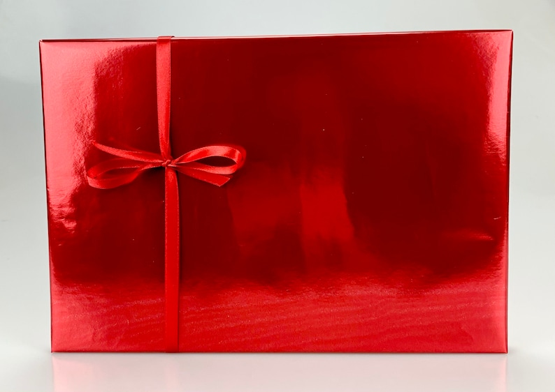May include: A rectangular, glossy red gift box tied with a matching red satin ribbon and bow. The box has a reflective surface, suggesting a metallic or lacquered finish. The ribbon is centered vertically and tied in a neat bow.