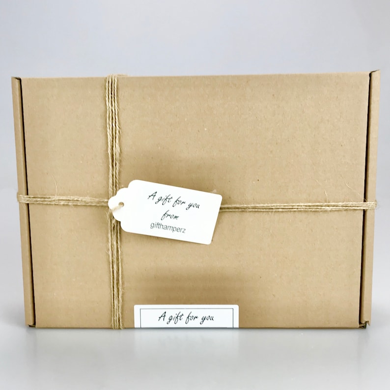 May include: A rectangular brown cardboard gift box tied with twine. A white tag with the text "A gift for you from gifthamperz" is attached. A smaller label at the bottom reads "A gift for you".