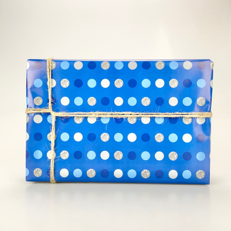 May include: A rectangular gift wrapped in blue paper with a polka dot pattern in shades of blue, silver, and white. The gift is tied with natural twine.