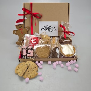 May include: A brown cardboard gift box tied with a red ribbon, filled with various vegan treats. Includes cookies, a gingerbread man, marshmallows, and a card that says "Vegan".