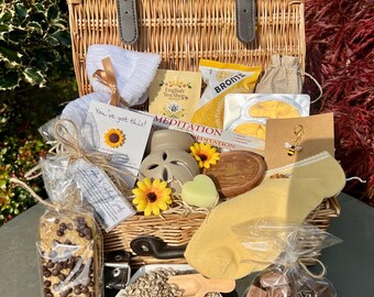Cesta de bienestar: té, chocolate, regalos para la relajación, autocuidado, atención plena, girasol y abeja.