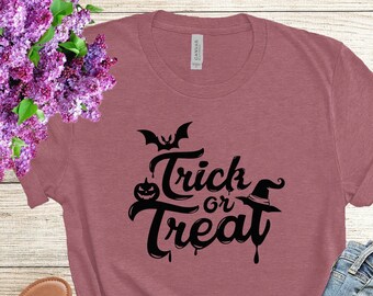 May include: A mauve t-shirt with a black graphic that says "Trick or Treat" with a witch's hat, a bat, and a pumpkin.