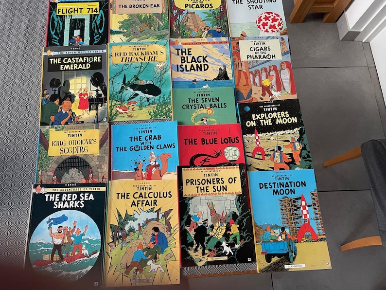 Peut inclure: Une collection de bandes dessin&eacute;es Tintin, pr&eacute;sentant divers titres aux couvertures color&eacute;es. Les titres incluent "Vol 714 pour Sydney", "L'Oreille cass&eacute;e", "Les Bijoux de la Castafiore" et "Le Tr&eacute;sor de Rackham le Rouge". Les livres sont dispos&eacute;s sur une surface.