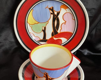 May include: A vintage teacup and saucer set with a red and black striped border. The cup and saucer feature a colorful abstract design of trees and clouds.