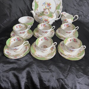 May include: A vintage tea set with a green and floral pattern. The set includes a teapot, creamer, sugar bowl, and six teacups and saucers.