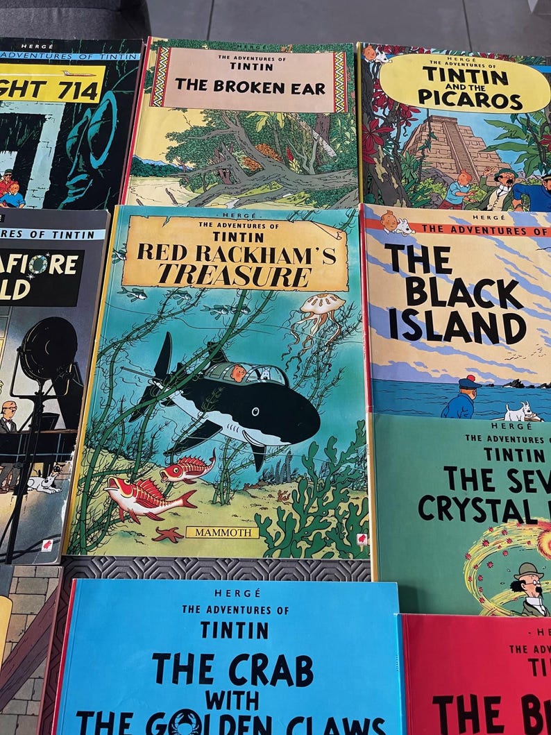 Peut inclure: Plusieurs bandes dessin&eacute;es Tintin, avec des couvertures illustr&eacute;es. Les titres incluent "L'Oreille Cass&eacute;e", "Le Tr&eacute;sor de Rackham le Rouge", et "L'&Icirc;le Noire". Les couvertures sont color&eacute;es, avec le nom de l'artiste, Herg&eacute;. Les livres sont de couleurs vari&eacute;es, dont le bleu, le jaune et le rouge.