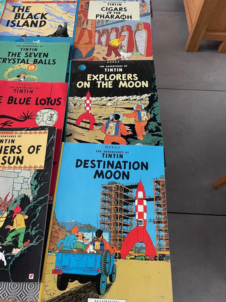 Peut inclure: Plusieurs bandes dessin&eacute;es Tintin, avec des titres comme "L'&Icirc;le Noire", "Les Cigares du Pharaon", "Les Sept Boules de Cristal", "On a march&eacute; sur la Lune", et "Objectif Lune". Les couvertures sont illustr&eacute;es.