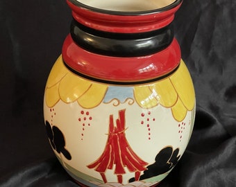May include: A red and yellow ceramic vase with a black rim and a painted design of a red pagoda with yellow clouds and black silhouettes.