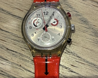May include: A clear plastic Swatch chronograph watch with a silver face and red accents. The watch has a red and black patterned strap with a phone icon.