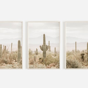 May include: A set of three framed prints featuring a desert landscape with tall cacti in muted tones of green, brown, and beige.