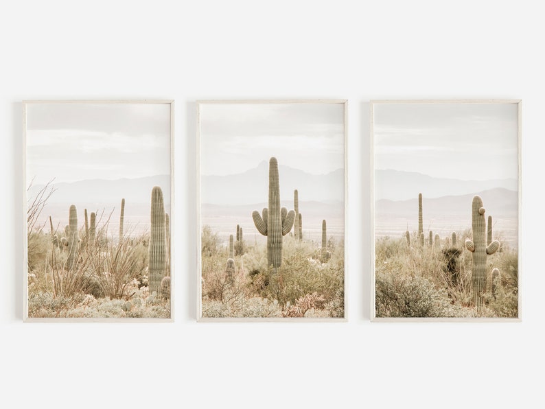 May include: A set of three framed prints featuring a desert landscape with tall cacti in muted tones of green, brown, and beige.