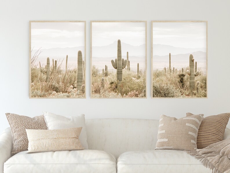 May include: A set of three framed prints featuring a desert landscape with tall cacti and a hazy mountain range in the background. The prints are in a minimalist style with a muted color palette.