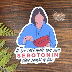 May include: A sticker featuring an illustration of a person in a blue shirt holding a red bowl and spoon. The text reads "If you can't make your own SEROTONIN store bought is fine." The Bipolar Creative logo is in the upper right corner.