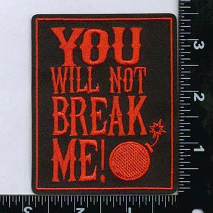 May include: Black rectangular patch with red embroidered text that reads "YOU WILL NOT BREAK ME!" A red bomb graphic is below the text. The patch is approximately 2.5 inches by 2 inches.