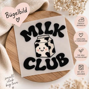 Könnte beinhalten: Ein quadratisches Bügelbild mit dem schwarzen Schriftzug MILK CLUB in einer fetten, geschwungenen Schrift. In der Mitte befindet sich eine weiße Milchkarton-Grafik mit schwarzen Kuhflecken und einem lächelnden Gesicht.