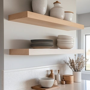 May include: Two wooden shelves with white ceramic bowls, plates, and vases. The shelves are mounted on a white wall.