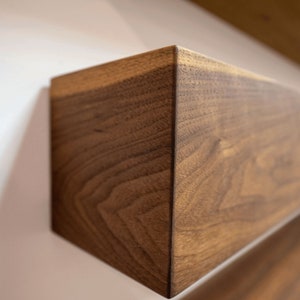 May include: Close-up of a dark brown wooden shelf with a natural wood grain pattern. The shelf is angled and appears to be part of a larger shelving unit.