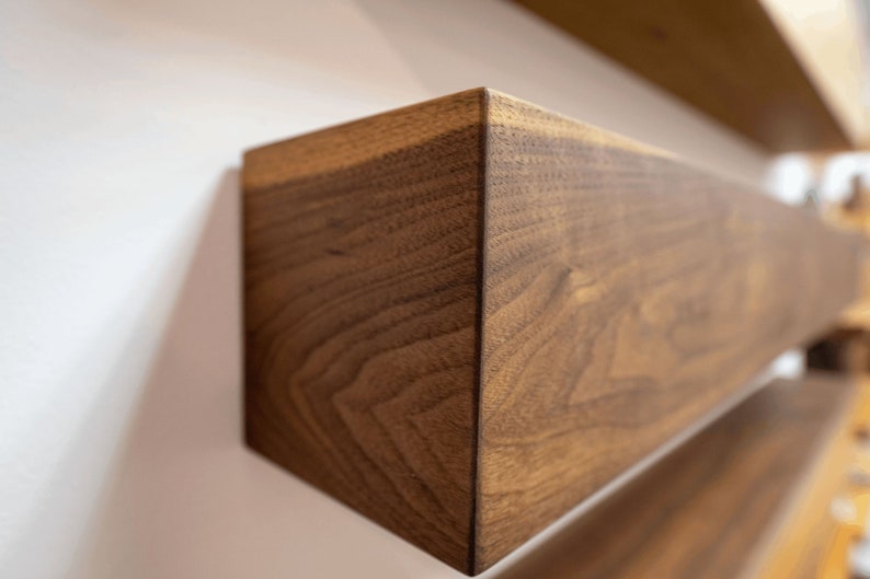 May include: Close-up of a dark brown wooden shelf with a natural wood grain pattern. The shelf is angled and appears to be part of a larger shelving unit.
