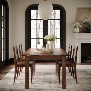 May include: A dark wood dining table with six chairs. The table has a natural wood finish and the chairs have a slatted back design. The table is set with a tray and a vase of white flowers.